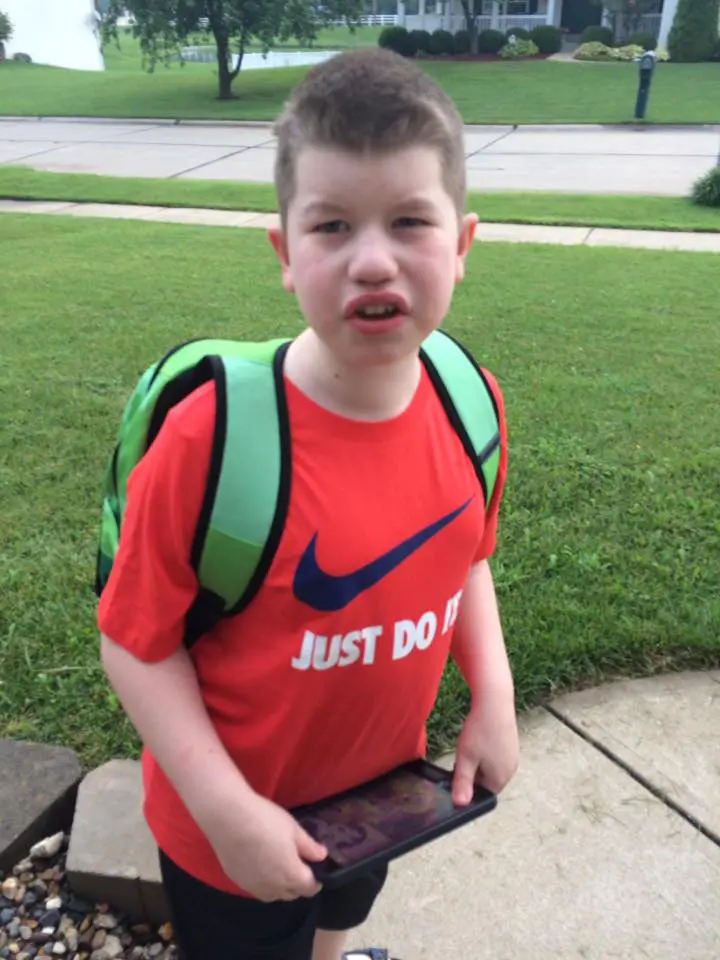Young boy with a backpack holding a tablet
