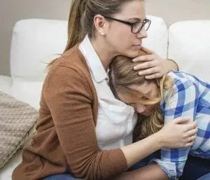 Woman comforting a distressed teen.