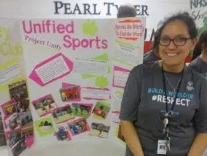 Sherry Wheelock smiling in front of a Unified Sports display board.