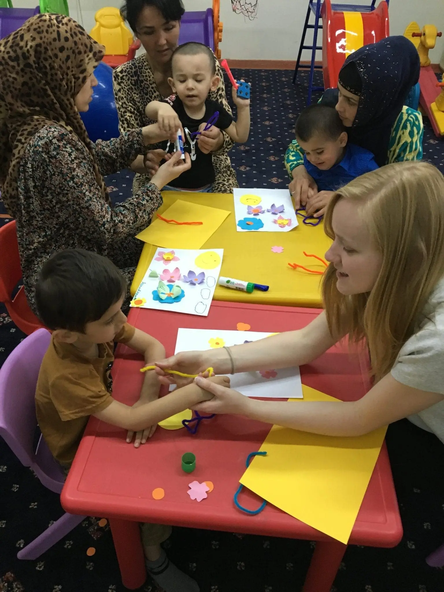 Adults and children at tables doing arts and crafts.