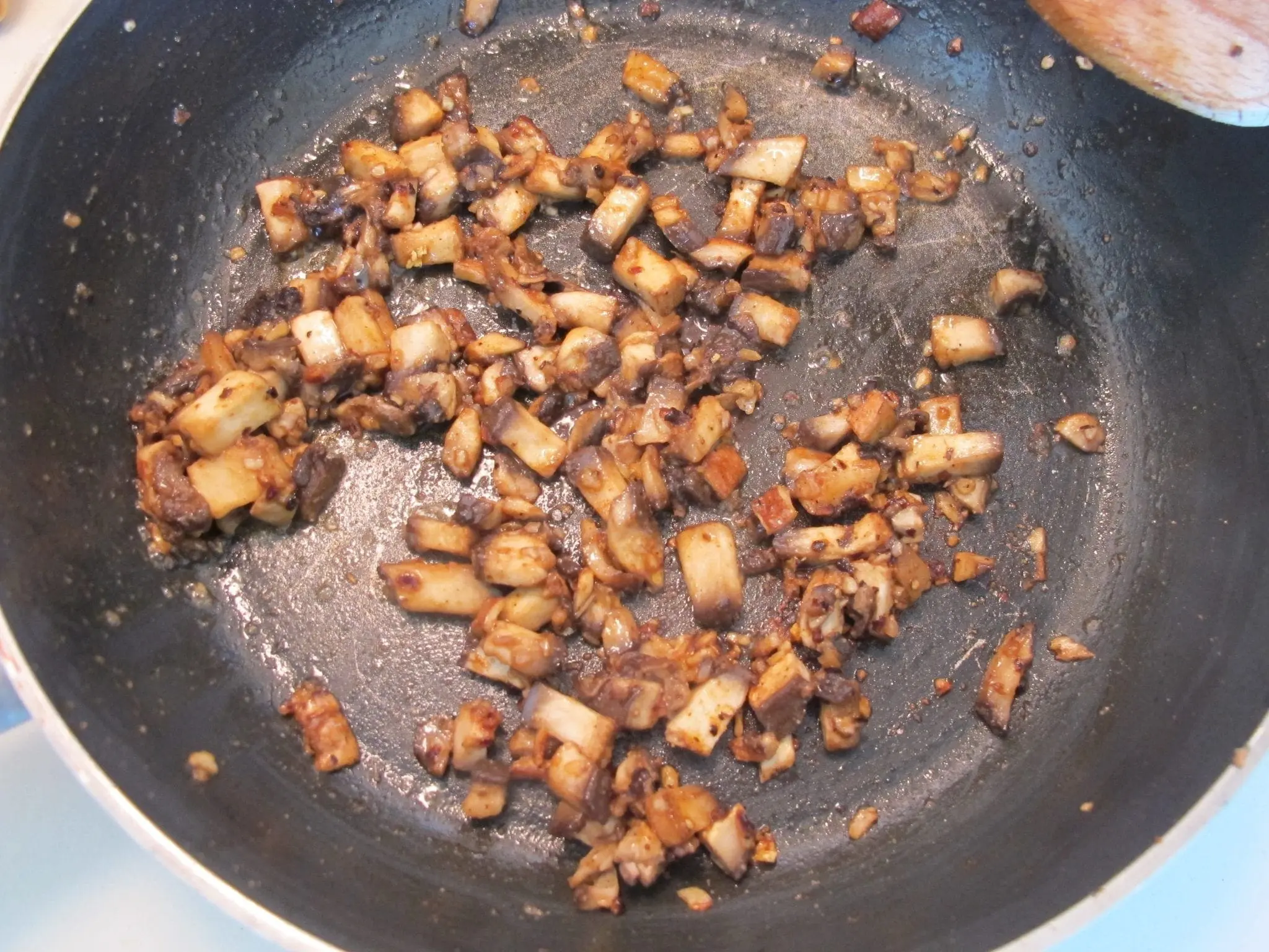 Diced mushrooms cooking in a pan.