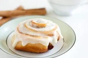 Cinnamon roll with white icing on a plate.