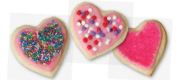 Three heart-shaped cookies decorated with pink frosting and sprinkles.