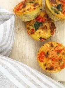 Four mini quiches with red peppers and spinach.