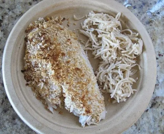 Panko crusted fish fillet with a side of pasta on a plate.