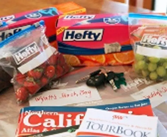 Food items in plastic bags, car keys, and travel guides on a table