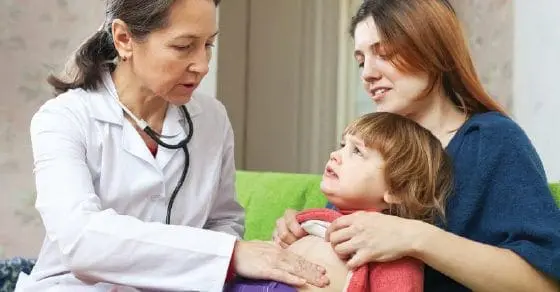 Doctor examining a child with a woman looking on.