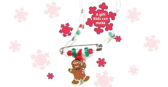 A gingerbread man ornament hangs from a safety pin necklace adorned with beads and a snowflake ornament that says "A gift Kids can make.