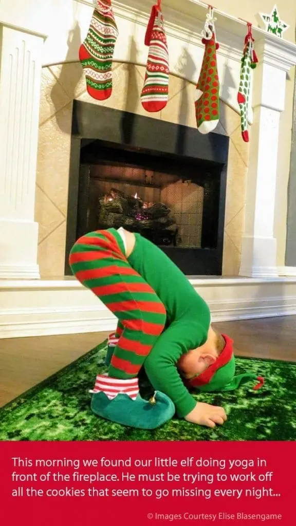 Child in elf costume doing yoga in front of a fireplace with stockings hanging above.