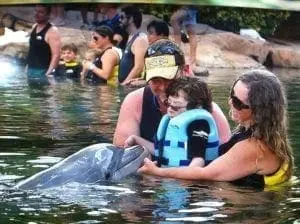 Allison Mooneyham with a child and a dolphin.