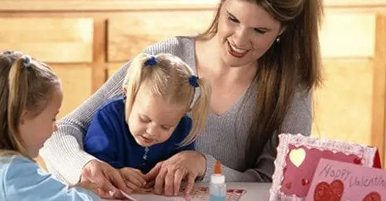 Woman and two children crafting a Valentine's Day card.