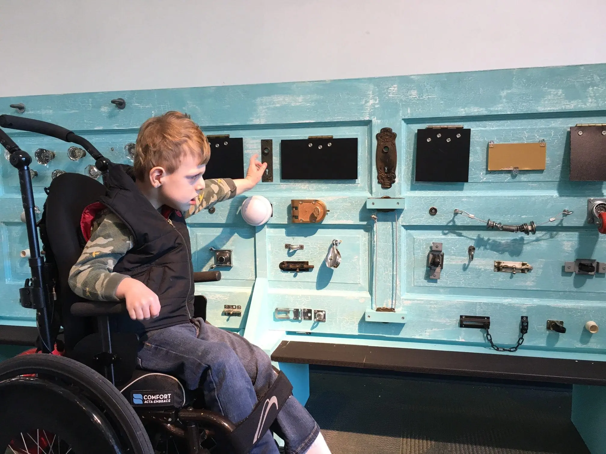 Child in wheelchair interacting with a sensory wall.