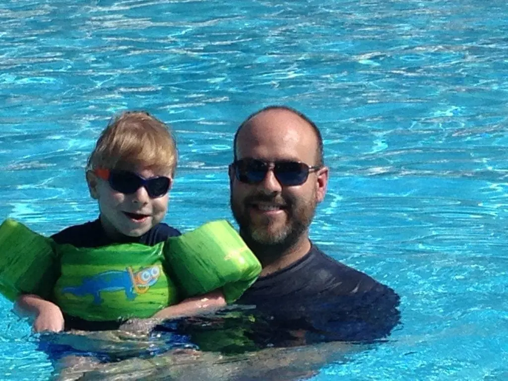 A man and a young child in a swimming pool.