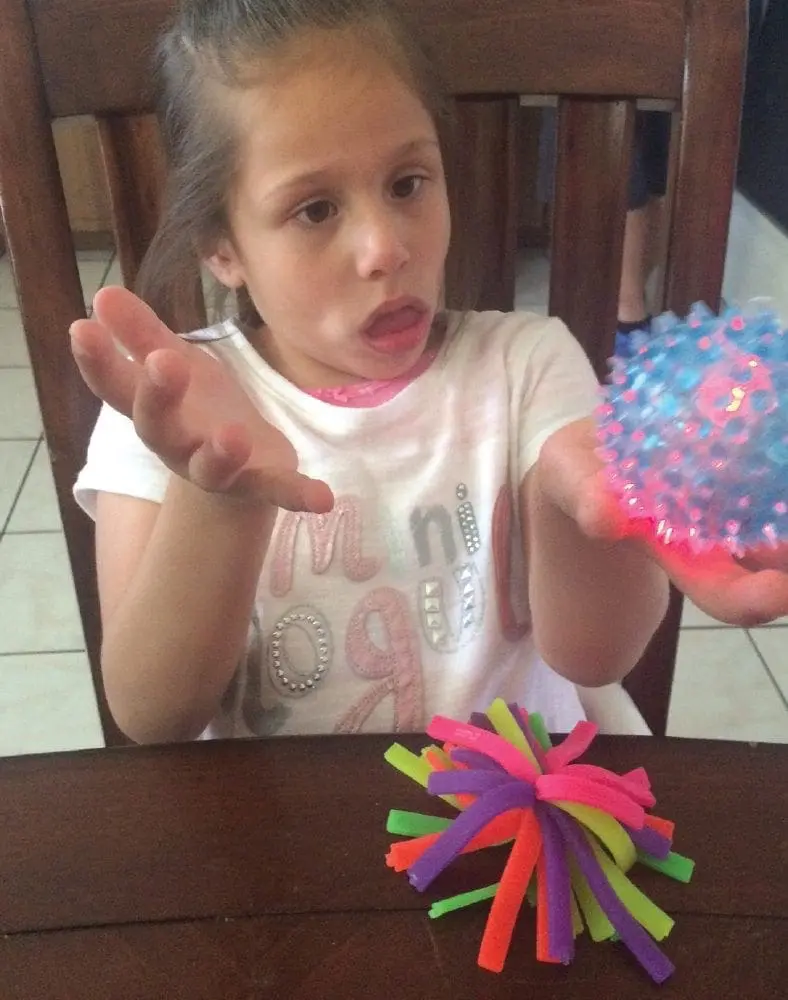 Child holding a spiky sensory ball and looking at the camera.