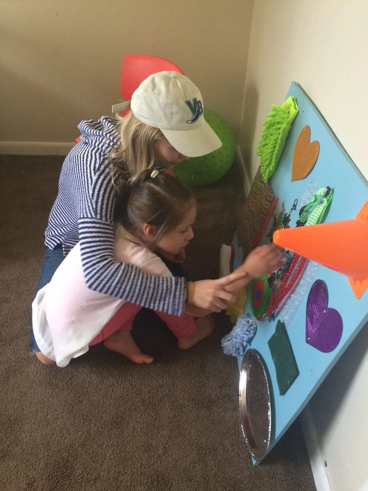 A woman and a young child interact with a DIY sensory board.
