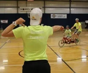 Staff member guiding a tandem bike rider during an iCan Bike program session.