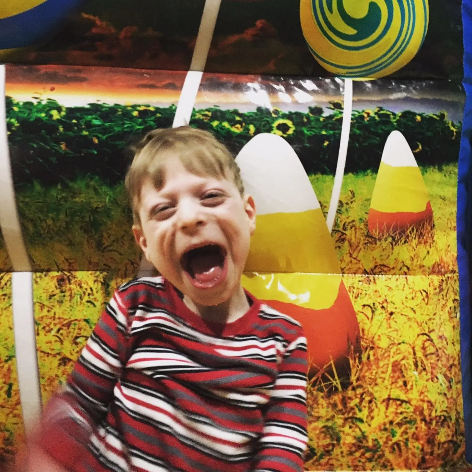 Boy with a striped shirt yelling in front of candy corn decorations