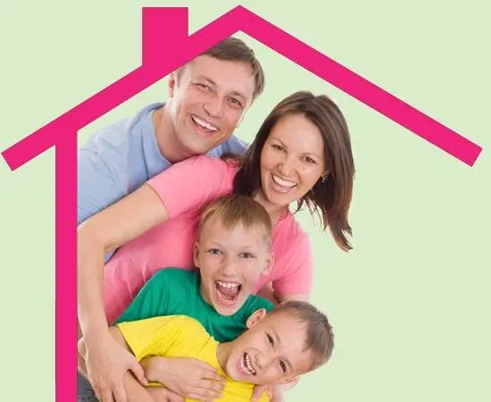 A smiling family of four embraces under a pink house outline.