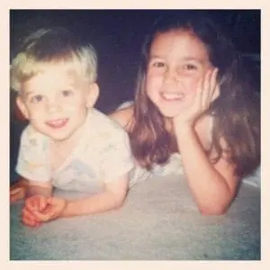 Two young siblings smile at the camera.