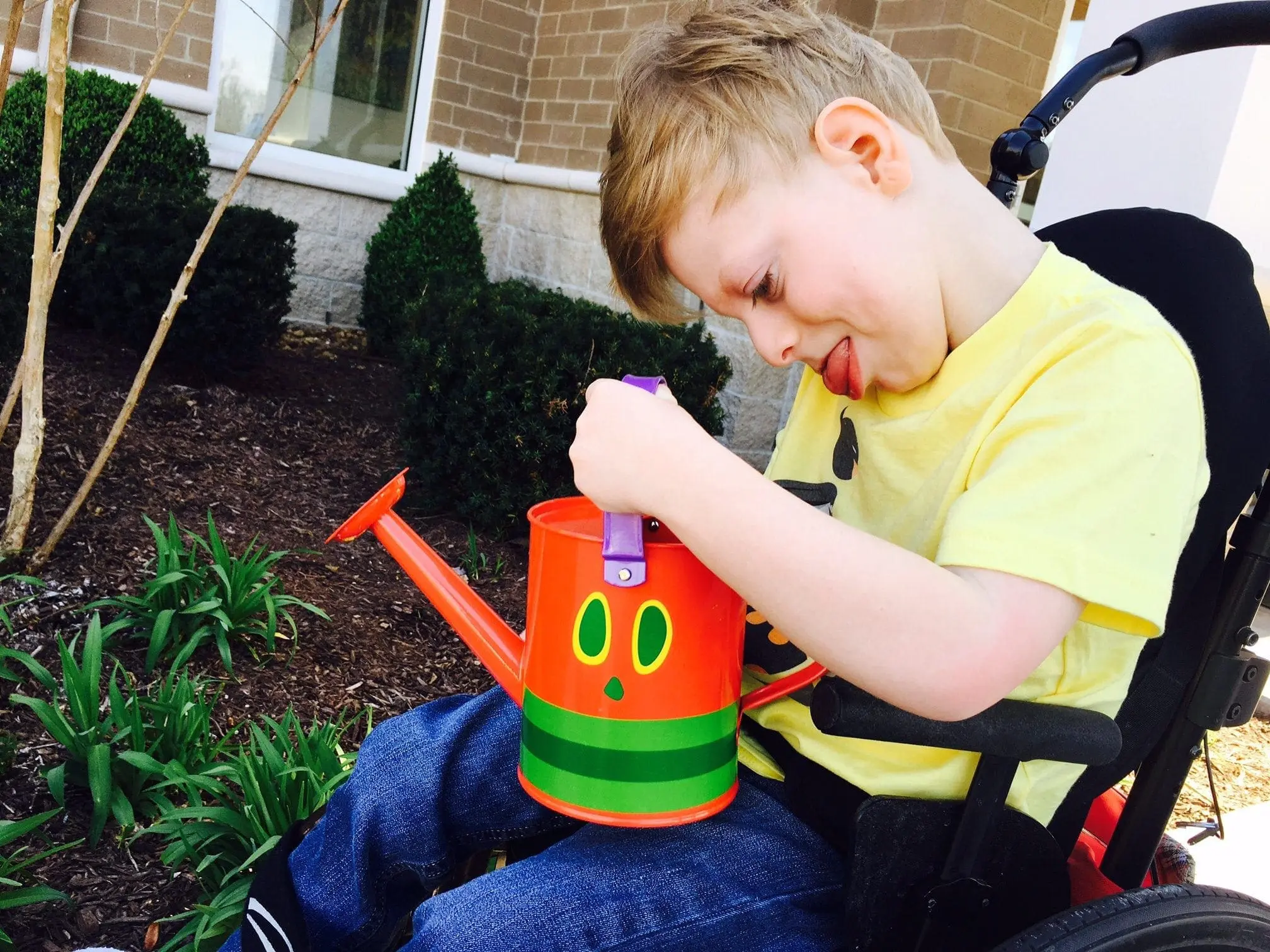Charlie watering a colorful watering can with a cartoon face.