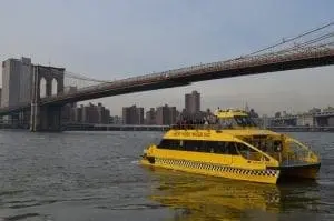 Yellow water taxi passes under the Brooklyn Bridge.