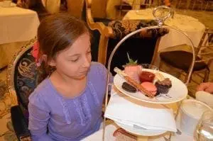 Girl in a wheelchair looks at a tiered plate of desserts.