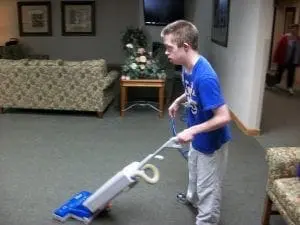 Nick vacuums a carpeted room.