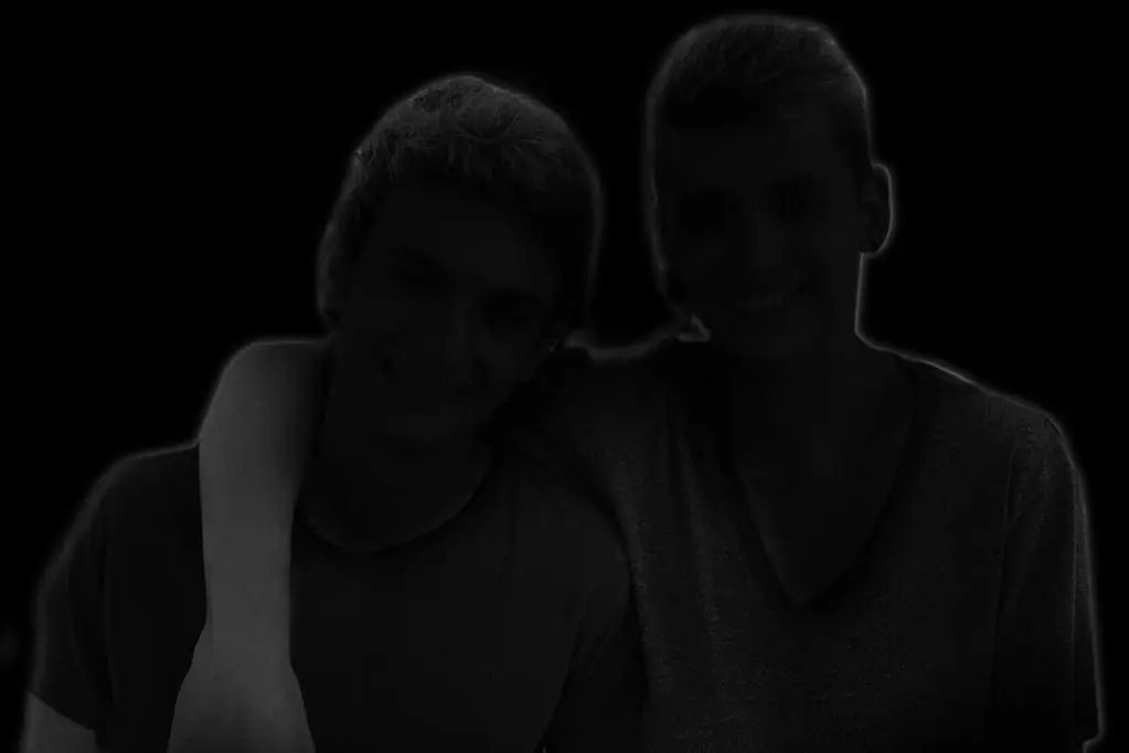Two young men with arms around each other.