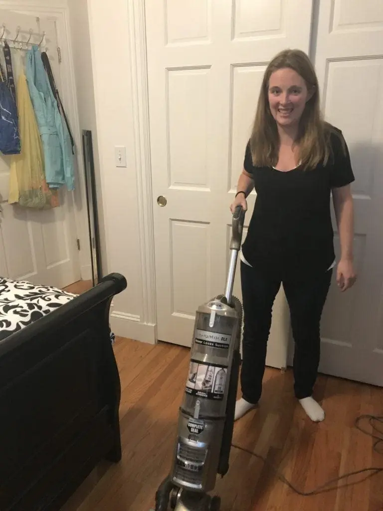 Caroline vacuums a bedroom floor.