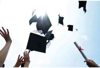 Graduation caps and a diploma are thrown into the air against a bright sky.