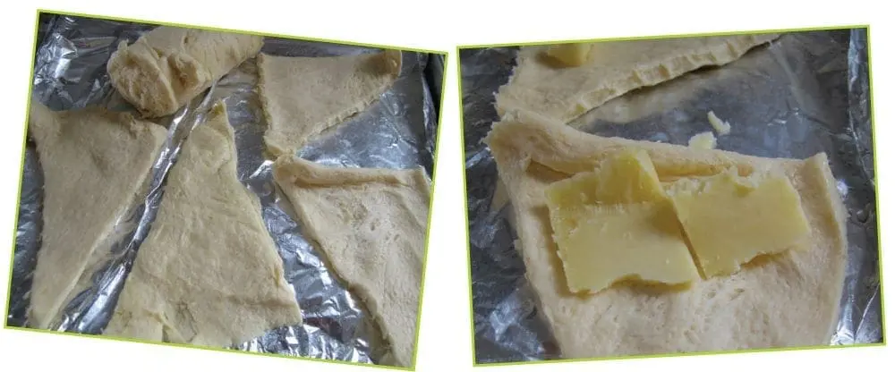 Croissant dough triangles on a baking sheet, with cheese slices on some of them