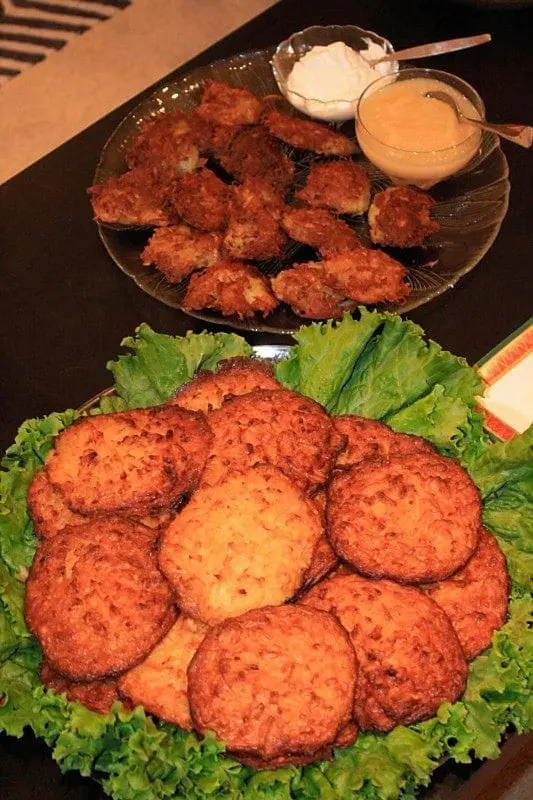 Latkas on a platter lined with lettuce, with two dipping sauces in bowls.