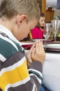 Boy and girl praying at a holiday table.