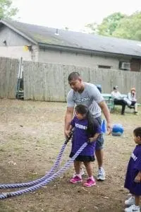 Man with a child holding battle ropes outdoors