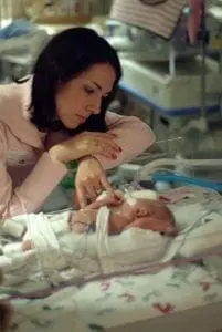 Jennifer Schwertfeger looking at an infant in a medical incubator.