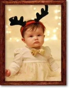 Baby wearing reindeer antlers and a festive dress.
