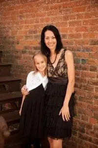 Grace and her mother standing in front of a brick wall.
