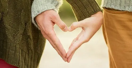Two people holding their hands together to form a heart shape.