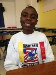 Benjamin smiling with two award ribbons pinned to his shirt.