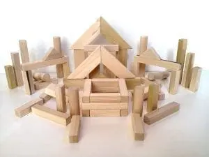 Wooden building blocks arranged in various structures on a white surface.