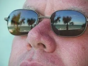 Palm trees reflected in sunglasses worn by a person.