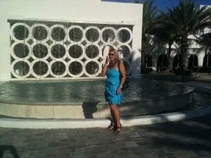 Woman in a blue dress standing by a fountain.