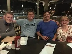 Four friends sitting at a table outdoors at night.