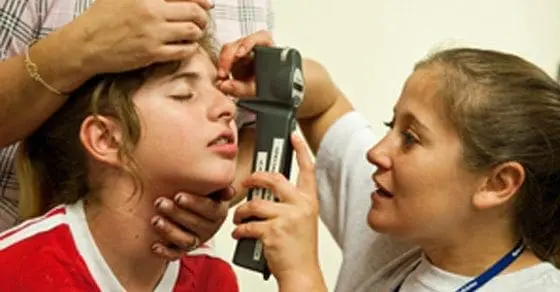 Child receiving an eye examination with a doctor using a medical device.