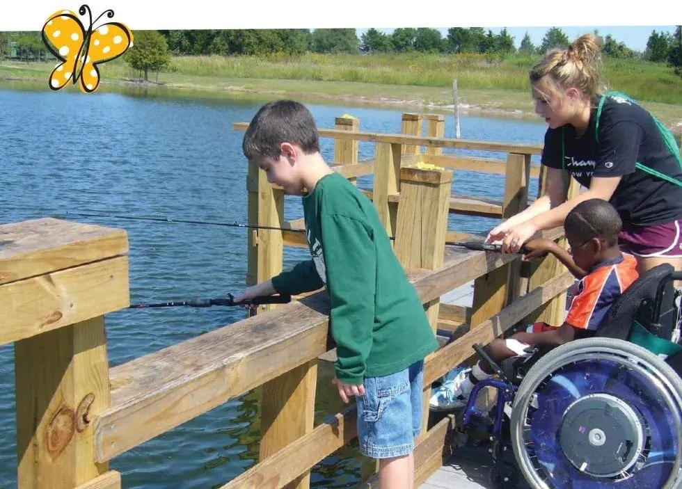Two children fishing from a dock with a counselor.