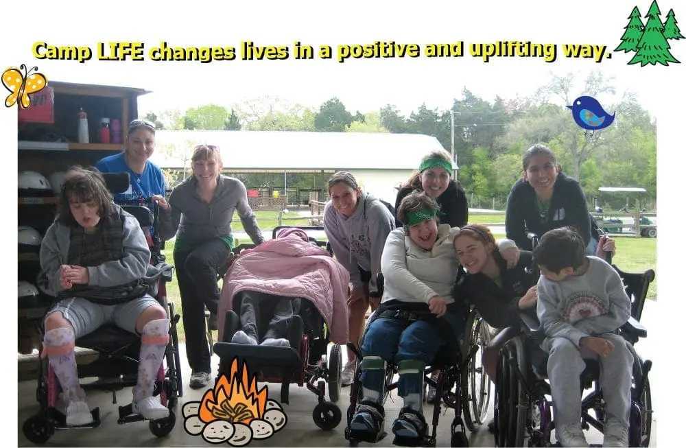 A group of campers and counselors are gathered around with some campers in wheelchairs.