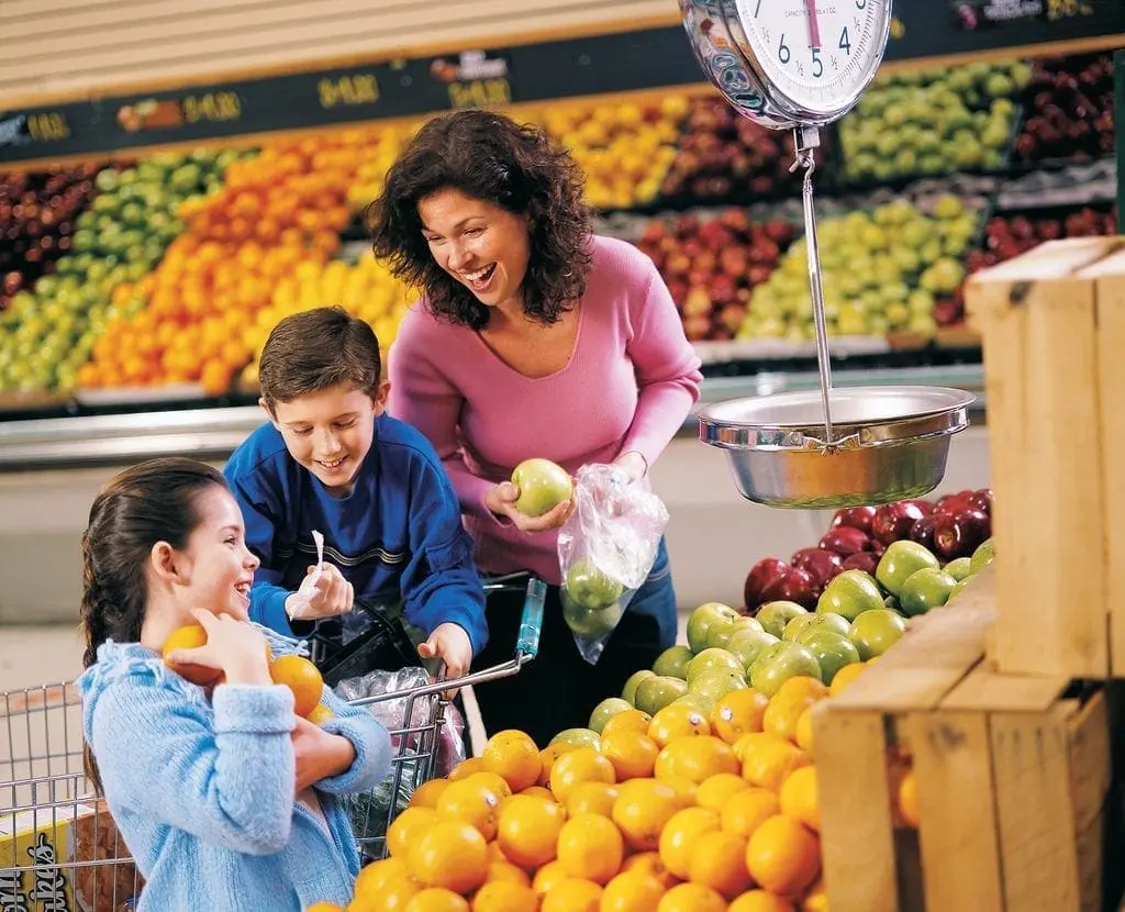 A mother and her two children shop for fruit in a grocery store.