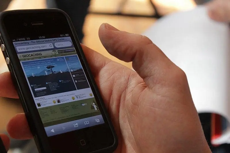 Hand holding a smartphone displaying a webpage with photos.