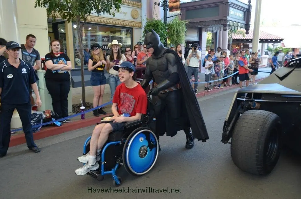 Batman stands next to a boy in a wheelchair.