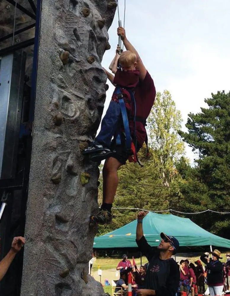 Jordan Cook climbing a rock wall at a camp.